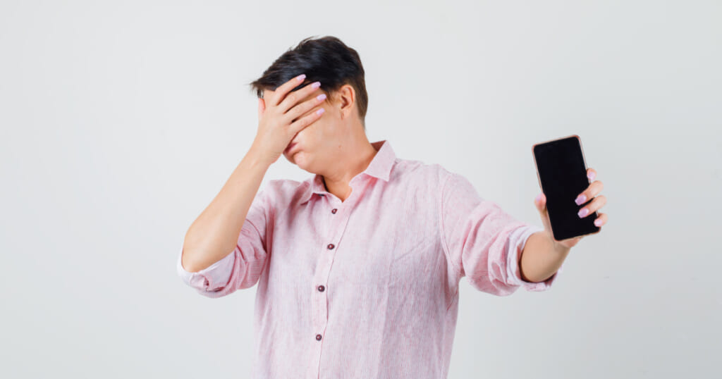 スマホを持って目を背ける男性