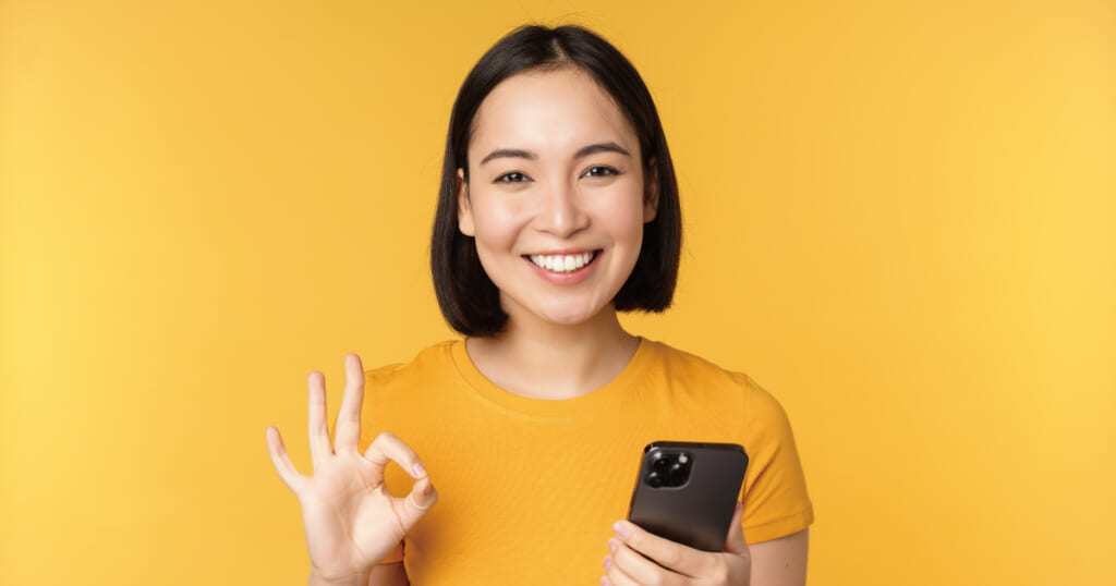 スマホを持って微笑む女性